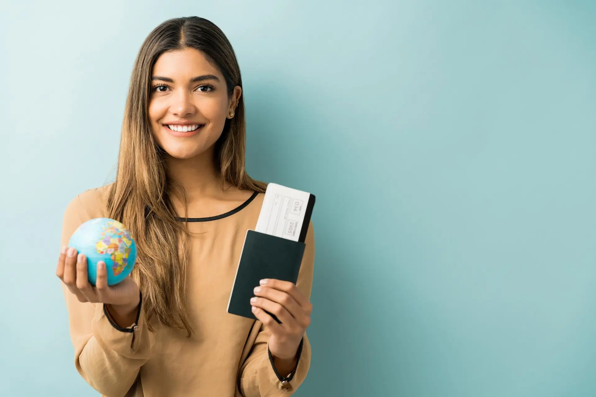 A student holding a small globe and a passport against a mint background